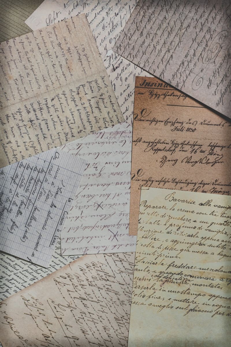 Handwritten letters and aged manuscript pages spread across a surface